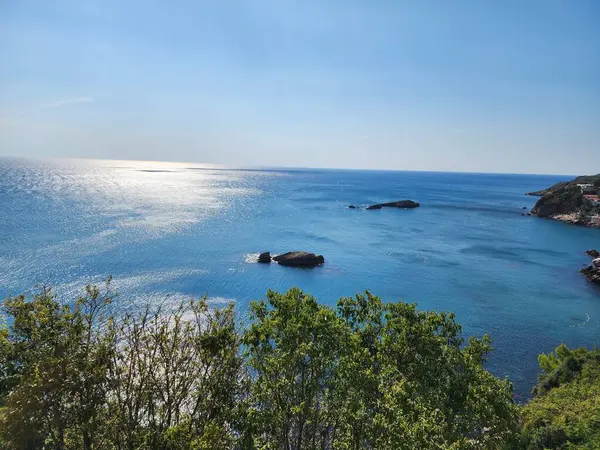 Güneşli bir günde mavi deniz kıyısında kayalar.