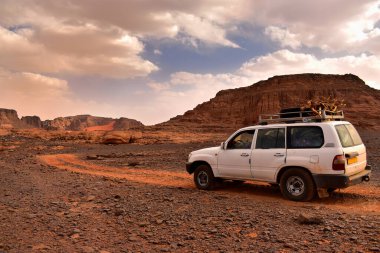 Sahra Çölü 'ndeki off-road arabası, engebeli arazide rutubetli raylar, virajlı yollar ve etrafındaki dağlar.. 
