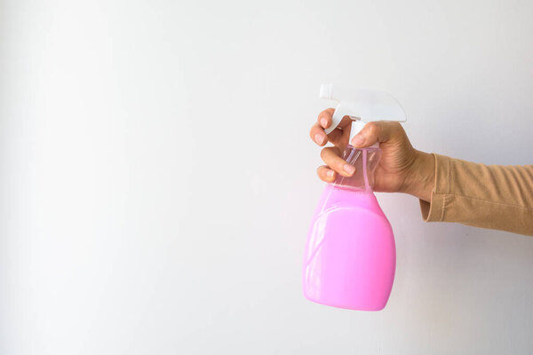 Woman hand-holding pink hygiene spray bottle. Isolated on a white background with copy space.