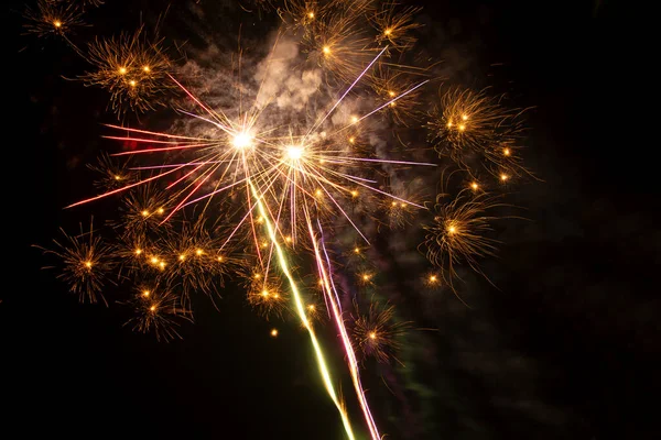 Açık gökyüzüne karşı yaz kutlamalarının olduğu bir gecede renkli havai fişekler.