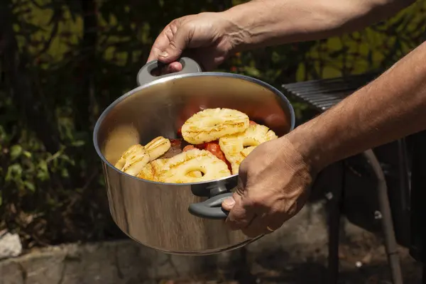 Yüksek çözünürlüklü metal bir tavanın sulu ızgara etleri ve ananas dilimleriyle dış mekânda çekilmiş görüntüsü.