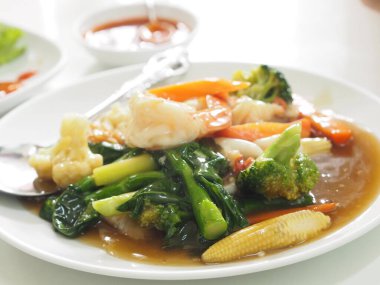 Tayland usulü yengeç omleti, beyaz tabakta yumurta sarısı yemek.