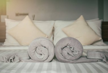 Modern yatak odasının iç kısmında güneşli bir sabah. Yatak odasında yastık yastık havlusu var. Yatak odası arka planında büyük parlak pencere ışığı. Yaz tatili boş bir otel odasında..