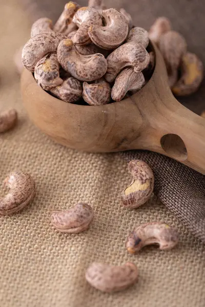 Roasted cashew nuts and halves in wooden bowl on table top view. Macro studio shot Homemade Roasted Salted Cashews in basket and spoon breakfast on sack, Healthy food Seeds snack product