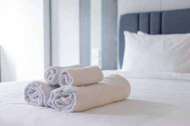 El değmemiş Beyaz Havlular: Lüks, Konfor ve Hijyen 'i vurgulayarak, Konforlu Bir Otel Odasında, Yumuşak, Temiz Bir Yatak Üzerine Katlanmış ve Yığılmış