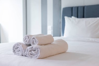 El değmemiş Beyaz Havlular: Lüks, Konfor ve Hijyen 'i vurgulayarak, Konforlu Bir Otel Odasında, Yumuşak, Temiz Bir Yatak Üzerine Katlanmış ve Yığılmış