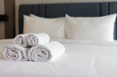 El değmemiş Beyaz Havlular: Lüks, Konfor ve Hijyen 'i vurgulayarak, Konforlu Bir Otel Odasında, Yumuşak, Temiz Bir Yatak Üzerine Katlanmış ve Yığılmış
