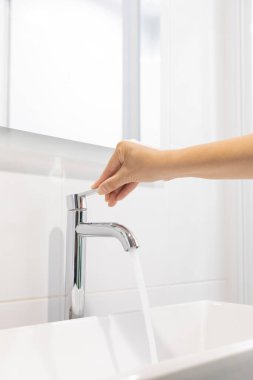 Kadın açık, krom musluk lavabosunu çek ve su musluğundaki corona virüsü için el sabunu yıka. Akan suyu itin. Lavabo lavabosunun musluğu olan banyo içi arka plan.