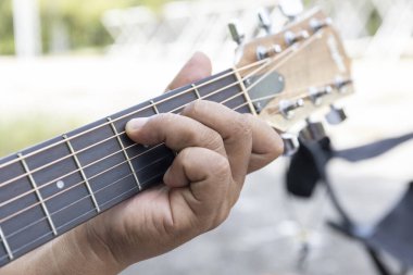 Gitaristin elleri hüner ve tutkuyla hareket eder, parmaklar akustik telleri koparır, notaları bir melodiye çevirir, bu melodi toplanmaya sıcaklık ve uyum getirir..