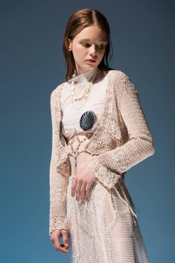 Modaya uygun, mavi arka planda duran etekli genç denizkızı. 