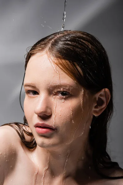 抽象的な灰色の背景に若いモデルの顔に注ぐ水 — ストック写真