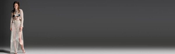 Young mermaid in fishnet skirt and knitted cardigan posing on grey background, banner 