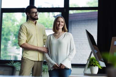 Smiling manager standing near young colleague on internship in office  clipart