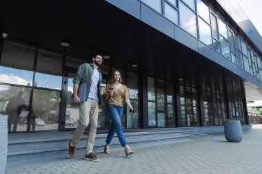 Kahve molası sırasında kağıt bardak ve cihazlar tutan genç iş adamları. 