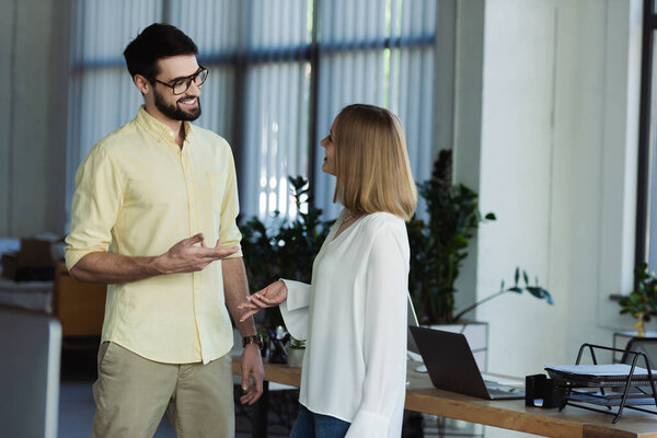 Smiling businessman talking to colleague on internship in office 
