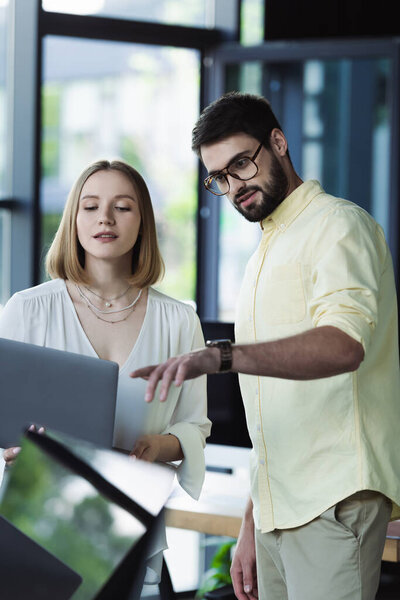 Бизнесмен указывает на ноутбук рядом с новым работником в офисе 