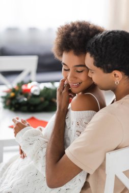 Esmer Afrikalı Amerikalı adam, bulanık mutfakta seksi kız arkadaşının yüzüne dokunuyor.