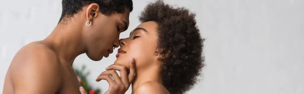 side view of shirtless african american man touching face of curly girlfriend, banner
