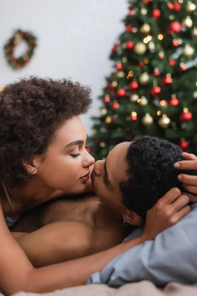 美国女人在家里的模糊的圣诞树旁亲吻男朋友 她是个卷曲性感的非洲女人 — 图库照片