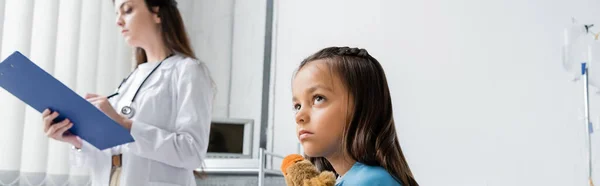 Niño Con Juguete Mirando Hacia Otro Lado Cerca Borroso Pediatra —  Fotos de Stock