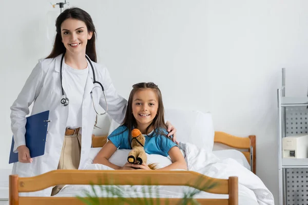 Médico Sorridente Abraçando Criança Feliz Com Brinquedo Macio Enfermaria Hospital — Fotografia de Stock