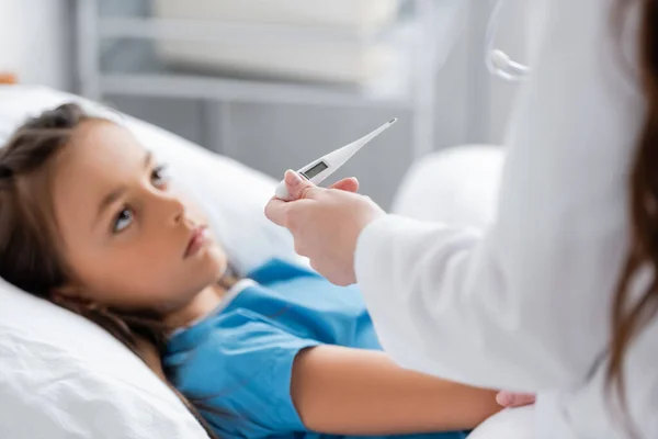 Doutor Casaco Branco Segurando Termômetro Eletrônico Perto Criança Turva Enfermaria — Fotografia de Stock
