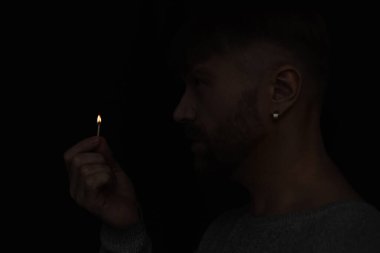 Enerji kesintisi sırasında yanan kibriti tutan adamın yan görüntüsü siyahta izole edilmiş.