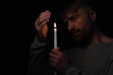 man in darkness caused by energy blackout holding lit candle isolated on black clipart