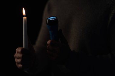 Yanan mum ve parlayan el feneri siyah üzerine izole edilmiş kırpılmış adamın ellerinde.