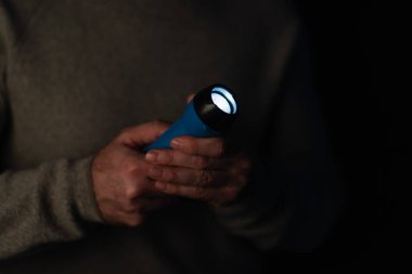 Karanlıkta parlayan el feneri siyah üzerine izole edilmiş kırpılmış adamın ellerinde.