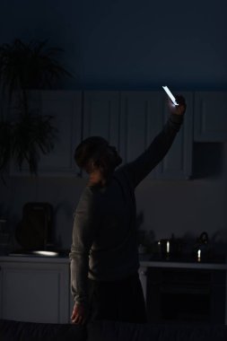 man searching for mobile connection while standing with smartphone in raised hand during power shutdown clipart