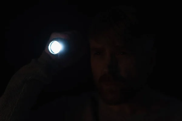 Uomo Con Torcia Luminosa Distogliendo Sguardo Nel Buio Isolato Sul — Foto Stock