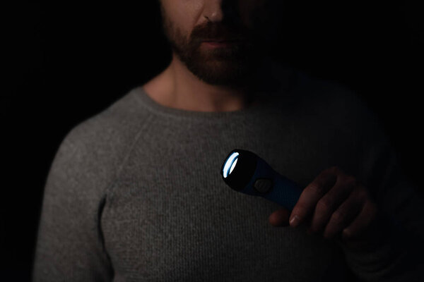 обрезанный вид человека, держащего светящийся фонарик во время отключения питания изолированный на черном