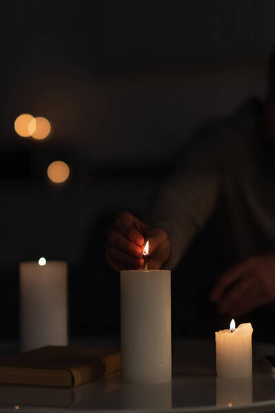 обрезанный вид человека зажигая свечи в темноте, вызванной отключением электричества