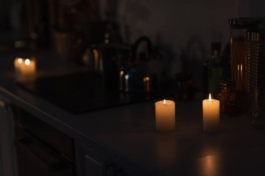 Enerji kesintisi sırasında mutfak tezgahında mutfak gereçleri ve yanan mumlar.