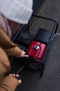 Elektrik kesintisi nedeniyle güç jeneratörünü çalıştıran bulanık adamın yüksek açılı görüntüsü