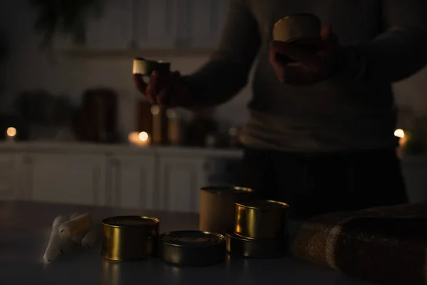 stock image partial view of man near reserve of canned food and candles during power outage