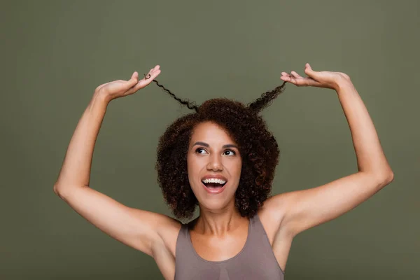 Позитивная Африканская Американка Трогает Кудрявые Волосы Смотрит Вверх Изолированным Зеленый — стоковое фото
