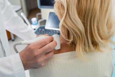 cropped view of doctor examining lymphatic system of blonde woman with ultrasound clipart