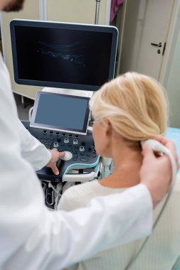 blurred doctor operating ultrasound machine during diagnostics of woman in clinic clipart