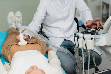 Beyaz önlüklü doktor yalancı kadının ultrasonunu çekiyor.