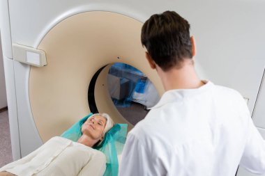 Bilgisayarlı tomografi tarayıcısında teşhis sırasında kadının yanında duran esmer doktor.