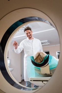 positive radiologist smiling at patient before procedure of computed tomography clipart