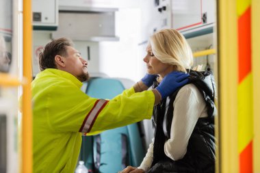 Lateks eldivenli sağlık görevlileri acil durum aracında hipertansiyonu olan orta yaşlı hastaları kontrol ediyor. 