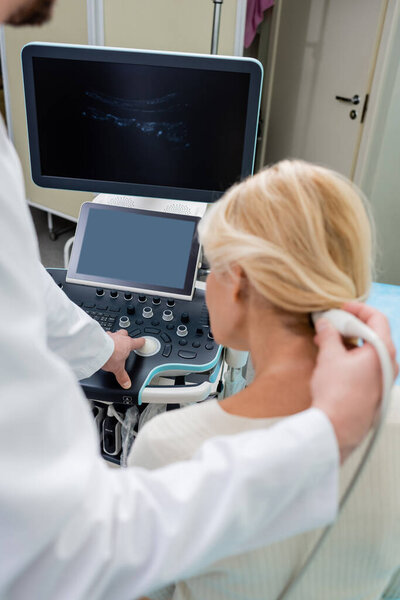 blurred doctor operating ultrasound machine during diagnostics of woman in clinic