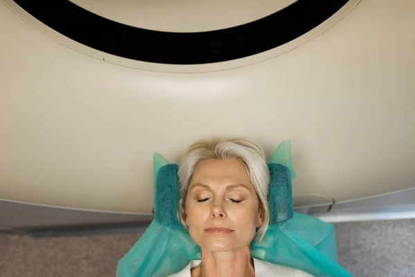 top view of blonde woman making diagnostics on computed tomography scanner in clinic