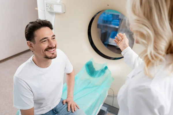 Bulanık Doktor Gülümseyen Hastanın Yanındaki Bilgisayarlı Tomografi Makinesini Işaret Ediyor — Stok fotoğraf
