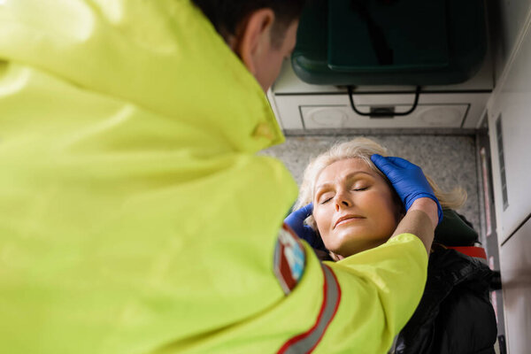 High angle view of blurred paramedic checking mature patient in emergency vehicle 