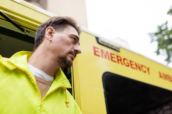 Dışarıdaki Bulanık Ambulans Aracının Yanında Duran Sağlık Görevlisinin Düşük Açılı — Stok fotoğraf