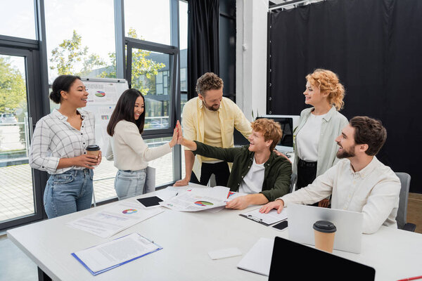 счастливые коллеги по межрасовому бизнесу дают пять членов команды и инфографику в конференц-зале